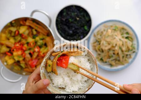Top view people have lunch in daily meal with Vietnamese vegan food, tofu skin cook with sauce, fried bamboo shoot, hand hold rice bowl and eating Stock Photo
