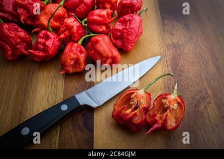Photograph of Carolina Reaper Peppers on a wood countertop with knife - The hottest peppers in the world! Stock Photo