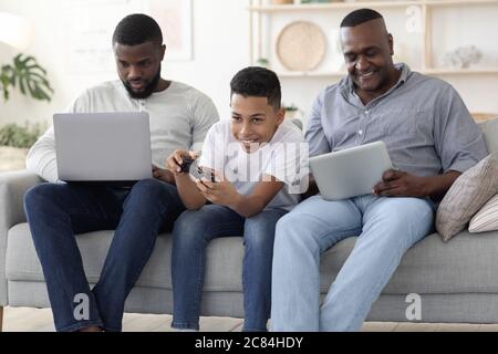 Male Family Pastime. Father, Son And Grandfather Spending Time With Different Gadgets Stock Photo