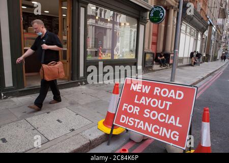 London, UK, 21 July 2020: A sign reads 'New Road Layout for Social Distancing' but some people choose not to distance themselves from work colleagues. Despite Prime Minister Boris Johnson urging people to return to work, the City of London is almost deserted. Usually it would be thronged with workers and tourists on a weekday morning. Anna Watson/Alamy Live News Stock Photo