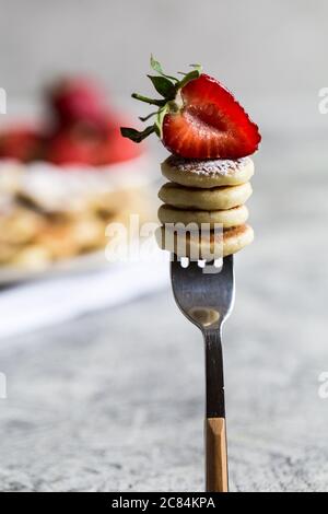 Tiny pancakes for breakfast. mini pancakes on a fork with strawberries Stock Photo