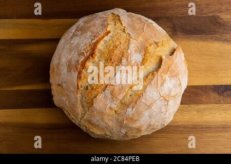Photograph of rustic white bread baked in a cast iron dutch oven, on a cutting board waiting to be sliced Stock Photo
