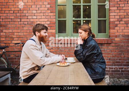 Side view of beautiful couple happily resting together in street cafe Stock Photo
