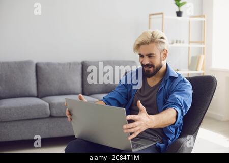 The guy works remotely with a laptop at home. Stock Photo