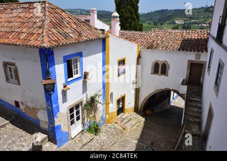 Obidos, Portugal - June 1, 2017: Charming medieval street of the old town Obidos in Portugal. Vila de Obidos national monument. Casa do Arco da Cadeia Stock Photo