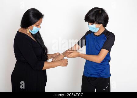 Indian woman ties Rakhi on her brother's hand on the occasion of Raksha Bandhan, You boy and woman wearing Covid protection masks Stock Photo