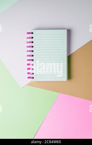 Open notebook with blank sheet and pink spiral on a colorful pastel background. The concept of education, writing down ideas, plans. Place for text. M Stock Photo