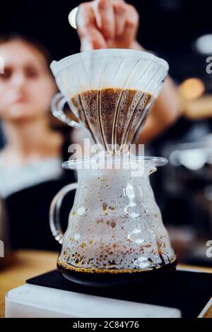 Drip coffee making with a funnel shaped filter paper on a glass vessel Stock Photo