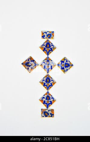 Ancient azulejo panel of tiles in cross shape on white plastered wall in medieval city Obidos. Typical old portuguese tiles with hand painted figures. Stock Photo