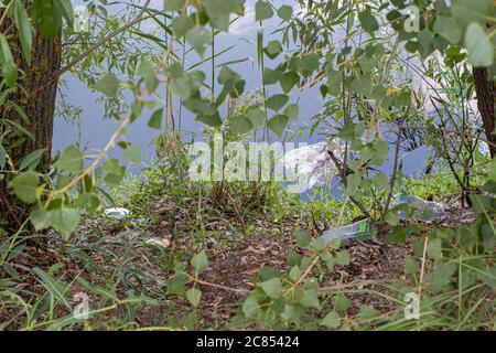 Debris, plastic on the shore of a beautiful lake. Pollution, human influence on the planet's ecology. Rubbish. Stock Photo
