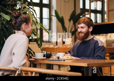 Young casual couple joyfully drinking coffee resting together in cafe Stock Photo