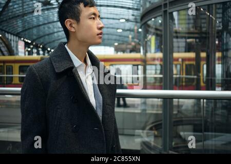 Side view of young Asian businessman thoughtfully looking away at subway station Stock Photo