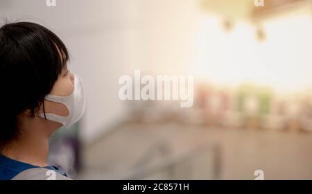 The asian girl wearing surgical mask pushing the trolley cart shopping the decorate funiture for interior inside the house in the big warehouse store. Stock Photo