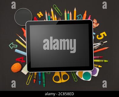Digital tablet and school supplies on blackboard Stock Photo