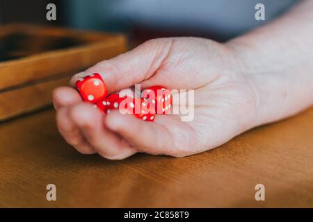 Female hand throwing  six red dices on the table. Yamb, dice game Stock Photo