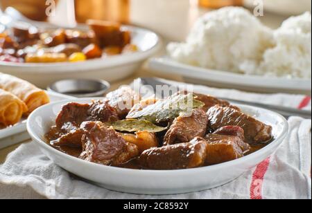 filipino pork adobo in bowl with rice in background Stock Photo