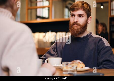 Young attractive man intently looking at girlfriend during coffee break in cafe Stock Photo