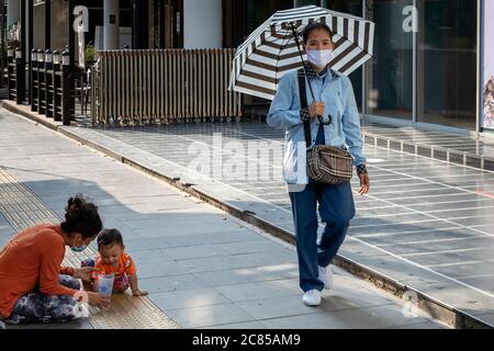 Woman wearing face mask with baby begging on the street during covid 19 pandemic, Bangkok, Thailand Stock Photo
