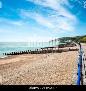 Eastbourne promenade and the South Downs, England. A bright, summer view west along the sea front towards the distant white cliffs and South Downs. Stock Photo