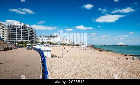 Eastbourne seafront, East Sussex, England. A bright summer view along the pebble beach of the seaside town with its pier visible in the distance. Stock Photo