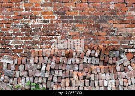 Old distressed red brick wall background texture with a pile of bricks in the foreground Stock Photo
