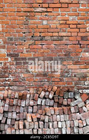 Old distressed red brick wall background texture with a pile of bricks in the foreground Stock Photo