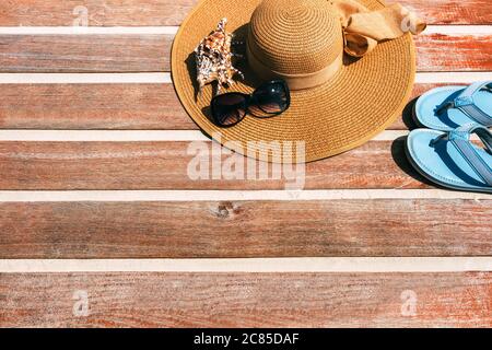 concept of vacation. Top view of a female straw hat on a wooden background with seashells and slippers. Copy place. Space for text or insertion. Beach Stock Photo