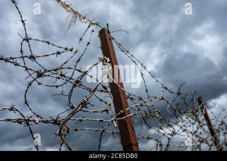 Ugly Old Barbed Wire On A Fence With An Overcast Sky And Copy Space Stock Photo