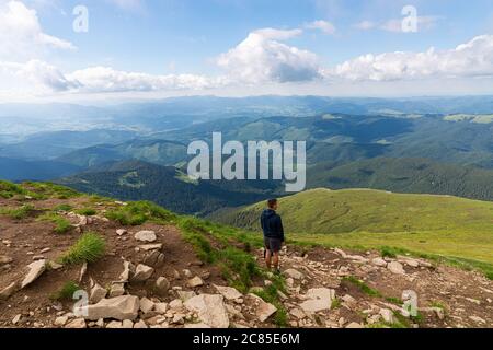 Rear View Of Man Standing On Cliff Against Sky Stock Photo