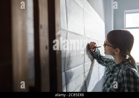 Close-up portrait of beautiful woman concentrated on work. Architect working in office with blueprints. Engineer sketching a construction project Stock Photo