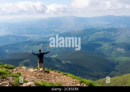 Hiker in silhouette stands on the rock in the beautiful mountains with rising hands at amazing landscape Stock Photo