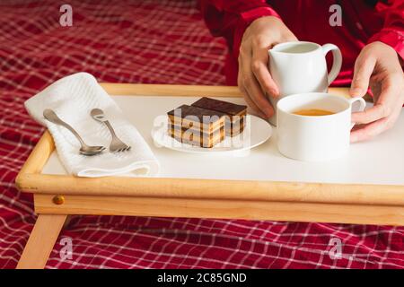 Cup of coffee with milk, and chocolate cake. Sweet delicious breakfast on a bed tray table Stock Photo