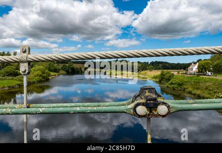 River Tweed, English/Scottish Border, United Kingdom, 21st July 2020. Bicentenary of Union Bridge: the bridge celebrates its 200th anniversary on 26th July. It was the first vehicular suspension bridge in the UK. At the time of its construction, it was the longest wrought iron suspension bridge in the world at 137m. It is still used regularly by pedestrians, cyclists and cars but cars must cross over it at a time. Cables of the bridge looking out over the River Tweed on the union border Stock Photo