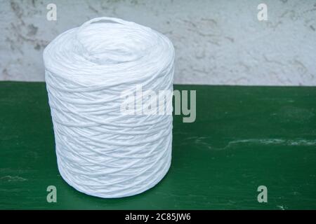 Spool with white twine on green table. Supplies and tools for handmade hobby leisure Stock Photo