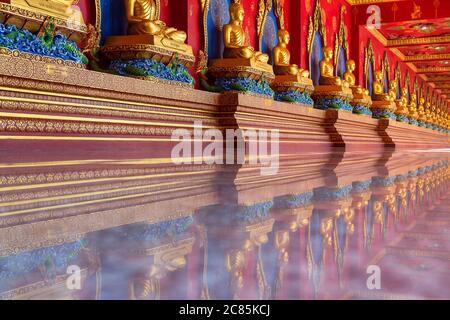 Many meditation Buddha statues are laid in rows on the corridor of Bang Tong Temple. Krabi Province, Thailand Stock Photo
