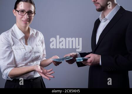 Portrait of two young businessmen in business clothes. A business woman in glasses, emotionally gesturing with her hands, is indignant at a small sala Stock Photo