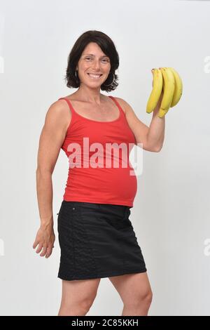 pregnant woman holding a banana on white background Stock Photo