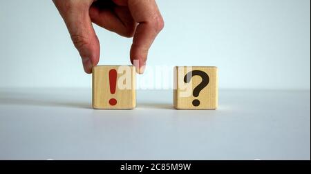 Hand making a choice between two cubes with exclamation mark and question marks on white background. Stock Photo