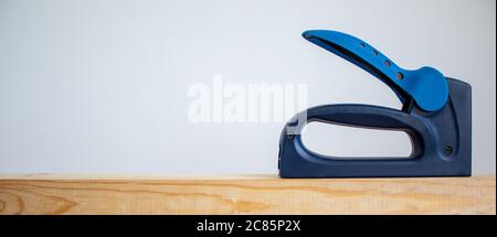 A construction stapler on a wooden bar. Beautiful white background. Copy space. Stock Photo