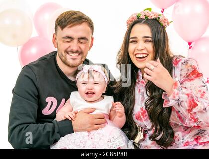 Horizontal lifestyle portrait of a young family on their daughter's first birthday. Stock Photo