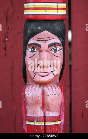 A detail of a carved, wooden totem pole featuring a Native American. Stock Photo