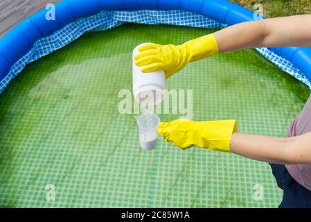 addition of chlorine powder for the pool to remove algae and disinfect water. inflatable swimming pool care concept. Stock Photo