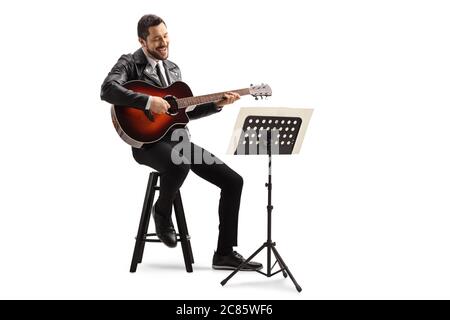 Musician playing an acoustic guitar and looking at a musical notebook on a stand isolated on white background Stock Photo