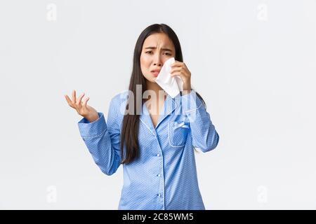 Heartbroken and depressed asian girl complaining on cheating boyfriend during sleepover, talking to girlfriend, wiping tears with napking, looking Stock Photo