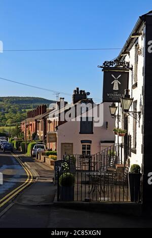 Early morning light illuminates the Wind Mill pub and the cottages along Mill Lane in Parbold. Beyond are the hills of Beacon Fell. Stock Photo