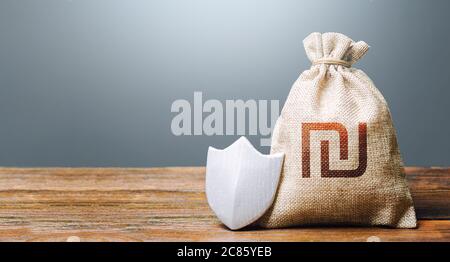 Israeli shekel money bag and protection shield. Ease doing business. Guaranteed deposits insurance compensation. Resistance to economic shock. Financi Stock Photo