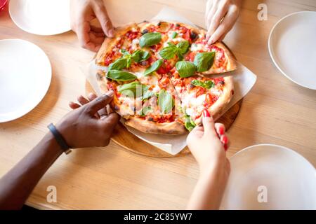 Cheerful Multiracial Friends Eating Delicious Vegetarian Organic Pizza With Basil Leaves At Pizza Hut Close Up Hands Stock Photo Alamy