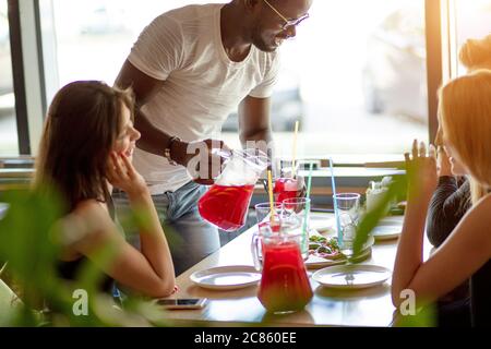 Pizza and Street dining Concept. Happy young smiling interracial couple spending time together with friends in cafe, eating pizza. Stock Photo