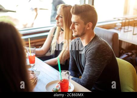 Hungry multiethnic male and female co-workers having lunch break together eating pizza in corporative diner, discussing working projects. Stock Photo