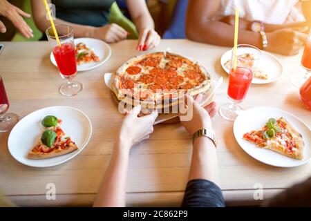 People sharing delicious hand made pizza at home - Close up of hands taking pizza pepperoni slice - Fast food, Street food, Italian Food and Party, Fr Stock Photo